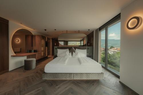 a bedroom with a large white bed and large windows at Gartenhotel Völser Hof - Adults Only in Völs am Schlern