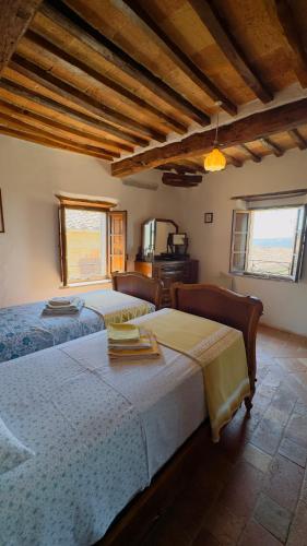 two beds in a room with wooden ceilings at La Nobiltà del Tempo in Murlo