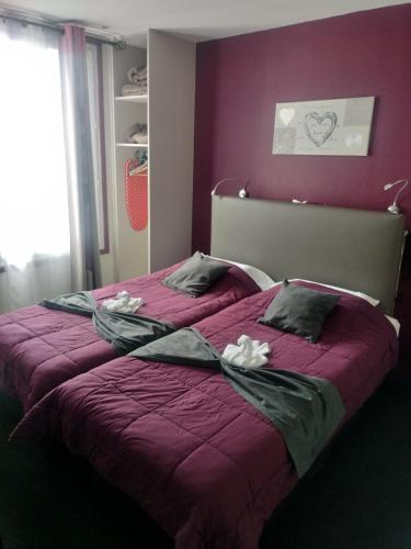 a bedroom with a purple bed with towels on it at Hôtel Montsouris Orléans in Paris