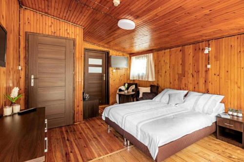 a bedroom with a bed and a wooden wall at Ośrodek Świt Wilga in Wilga