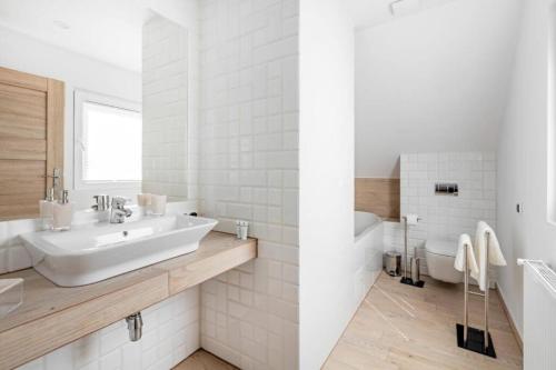 a white bathroom with a sink and a tub at Ośrodek Świt Wilga in Wilga