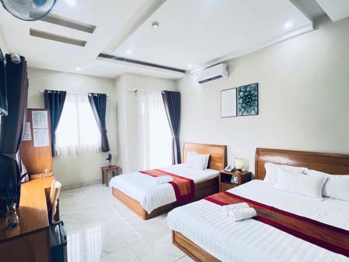 a hotel room with two beds and two windows at The Sun Hotel in Long Bình