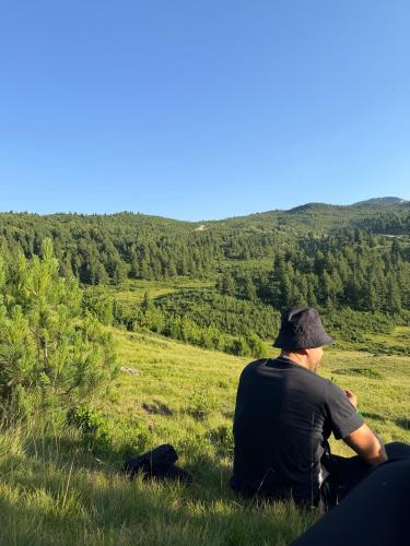 a man sitting in the grass looking out at a field at ILDO Guesthouse in Asim Zeneli