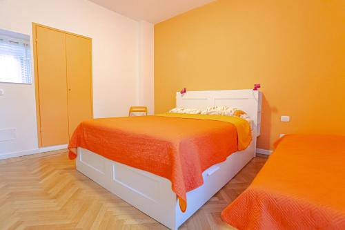 a bedroom with a bed with an orange blanket at Magnifica Terrazza - Lake View & Wi-Fi in Gardone Riviera