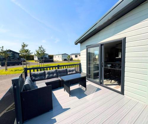 a patio with a couch and a table on a deck at Hilltop Holiday Park in Portrush