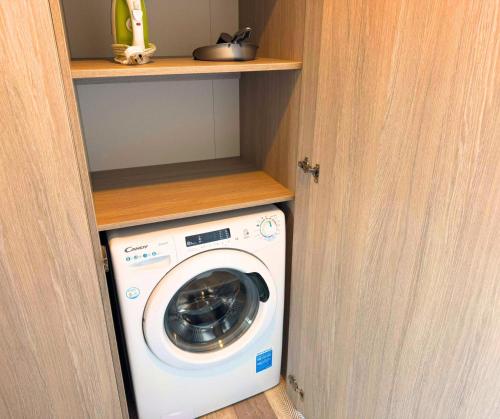 a washer and dryer in a closet with a door at Hilltop Holiday Park in Portrush