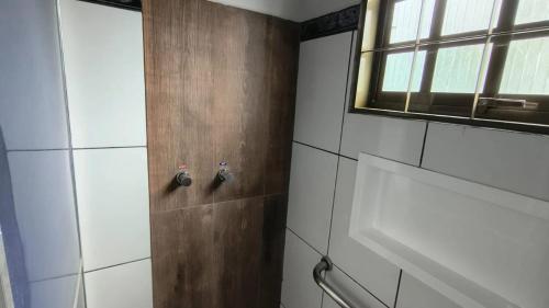 a bathroom with a shower with a wooden door at Hotel Pousada Narandiba in Narandiba