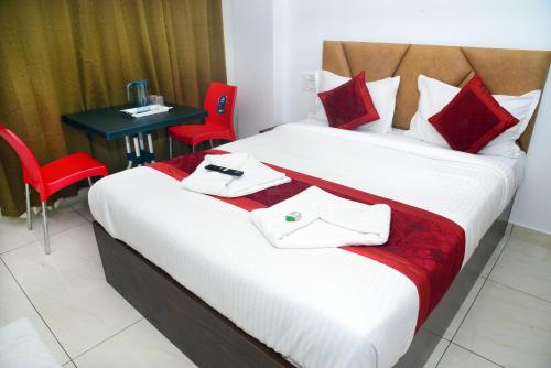 a bedroom with a bed with red chairs and a table at Hotel Dream Palace in Mysore