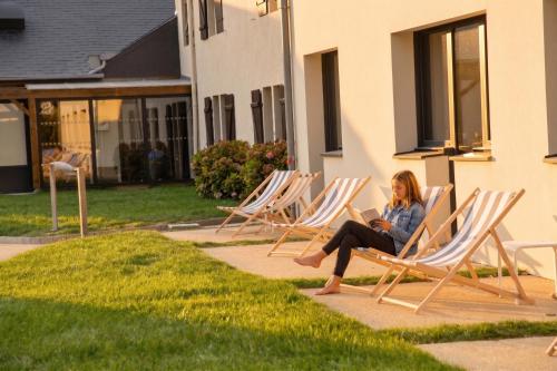 a woman sitting in lawn chairs reading a book at Kyriad Lannion-Perros-Guirec in Lannion