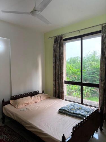 a bed in a bedroom with a large window at The Humble Abode in kolkata