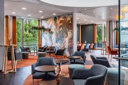 ein Wartezimmer mit Stühlen und Tischen und einem Wandgemälde in der Unterkunft Lifestyle Hotel Sedartis Lake Zurich in Thalwil