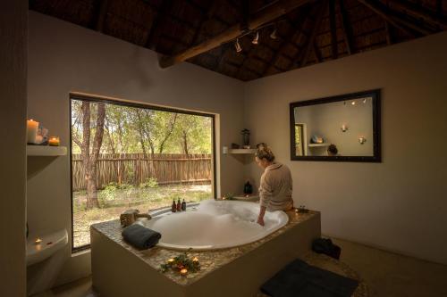 a woman standing in a bath tub in a bathroom at Tau Game Lodge in Madikwe Game Reserve
