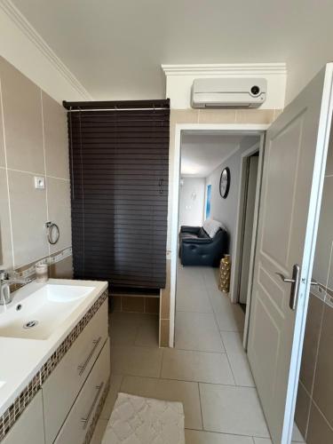 a bathroom with a sink and a room with a couch at Location Vias in Vias