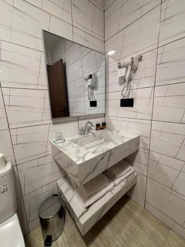 a white bathroom with a sink and a mirror at Hôtel City Center in Nador