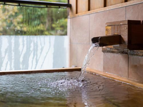 a water fountain in a pool of water at Okudogo Ichiyunomori in Matsuyama