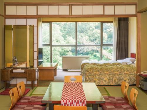 a bedroom with a bed and a large window at Okudogo Ichiyunomori in Matsuyama