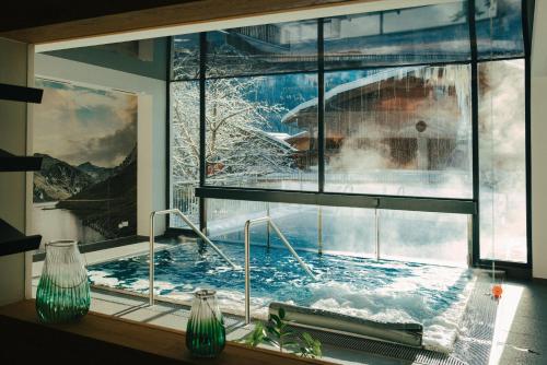 a room with a large window with a swimming pool at Venediger Lodge in Neukirchen am Großvenediger