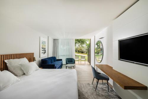 a hotel room with a bed and a flat screen tv at Hacienda Forest View Hotel in Ma'alot Tarshiha