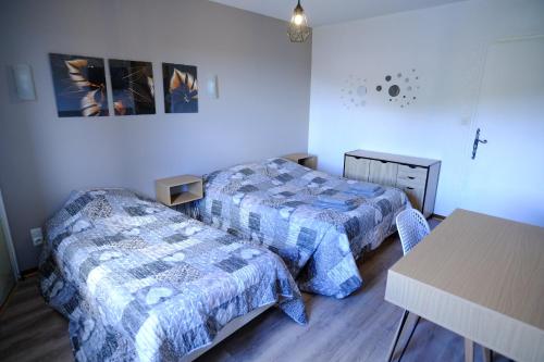 a small room with two beds and a table at AU CHAT BLEU in Saint-Laurent-les-Bains