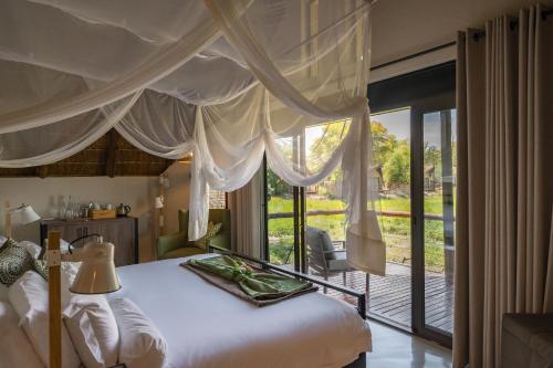 a bedroom with a bed and a large window at Tau Game Lodge in Madikwe Game Reserve