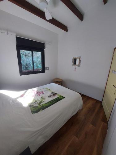 a bedroom with a white bed and a window at L'Oreiller du Maïdo in Saint-Paul