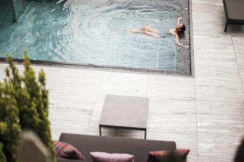 a couple of people swimming in a pool at Das Kaltenbach - ApartHotel in Kaltenbach