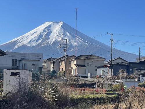 a snow covered mountain in the distance with houses at Villa Hello Fujisan ヴィラハローフジサン 屋根付きBBQ場 ワンちゃん大歓迎 A220 in Fujiyoshida