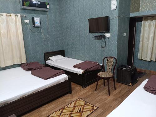 a room with two beds and a chair and a tv at SM Guest House in Lucknow
