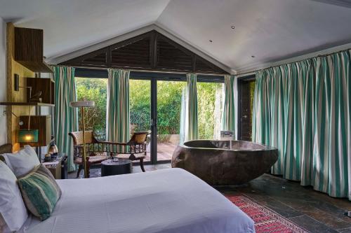 a bedroom with a large bed and a tub at La Mare aux Oiseaux, The Originals Collection in Saint-Joachim