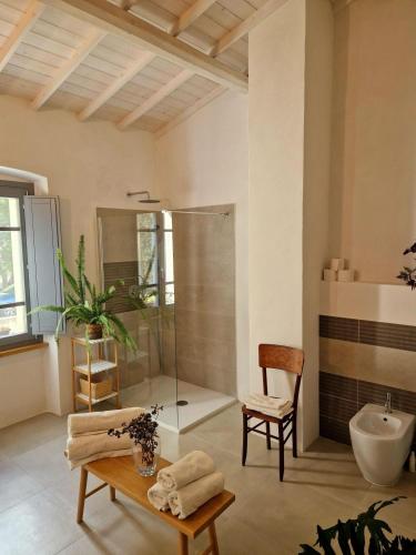 a bathroom with a shower and a table and a chair at Casa S'urtzula in Sini