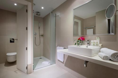 a bathroom with a sink and a shower and a toilet at Occidental Bilbao in Bilbao