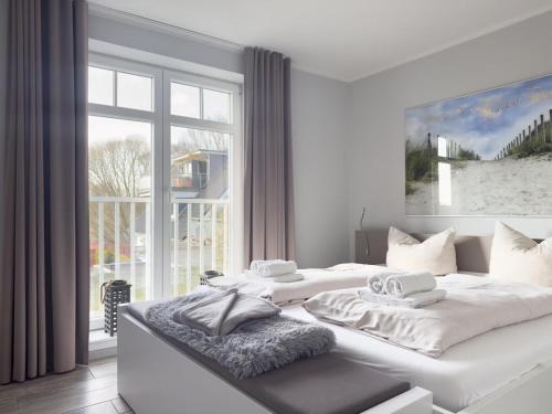 a white bedroom with a large bed with two towels at Ferienwohnung Baltic Lounge 53 in Haffkrug