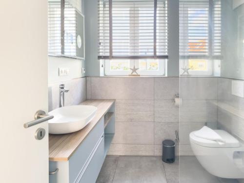 a bathroom with a sink and a toilet and windows at Ferienwohnung Baltic Lounge 53 in Haffkrug