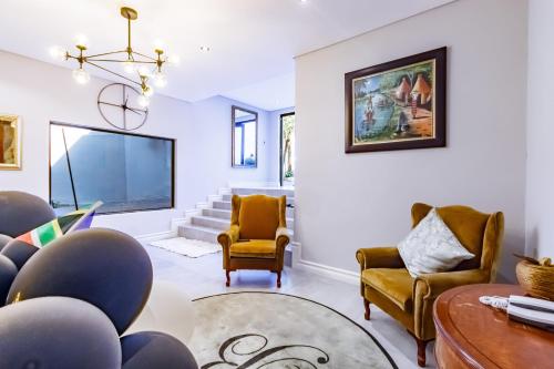 a living room with chairs and a large screen tv at Braham Lodge - The Octave in Johannesburg