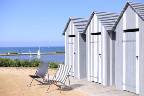 two chairs and a row of beach huts on the beach at Côte Ouest Thalasso & Spa Les Sables d'Olonne - MGallery Collection in Les Sables-dʼOlonne