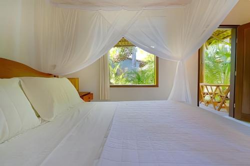 a bedroom with a white bed with a window at Licuri Praia de Algodões na beira do mar in Marau