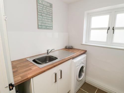 a kitchen with a sink and a washing machine at Canny Cottage in Belford