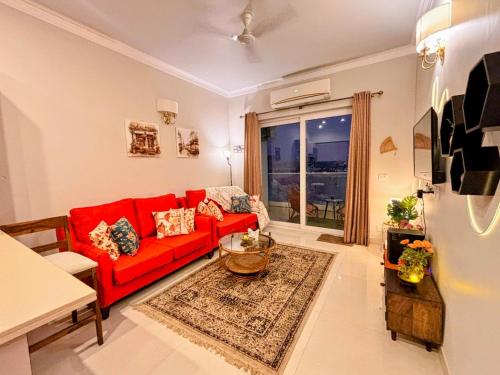 a living room with a red couch and a window at Romantic Sky Studio with Pool by The Nook in Sohna