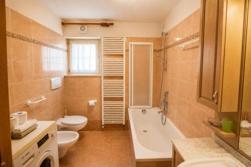 a bathroom with a tub and a toilet and a sink at Casa Cesarina by AMA Val di Fassa in Canazei