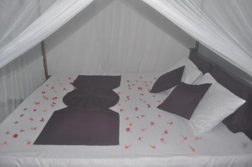 a white bed with red flowers on it at Talalla Mango House in Talalla South