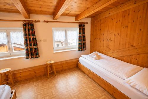 a bedroom with a bed and two windows at Casa Cesarina by AMA Val di Fassa in Canazei