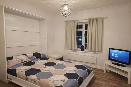 a bedroom with a bed and a flat screen tv at Newly Renovated Studio in Bishop's Stortford in Bishops Stortford