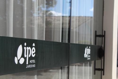 a green sign in front of a building at Ipê Hotel Jardins in Ponta Grossa