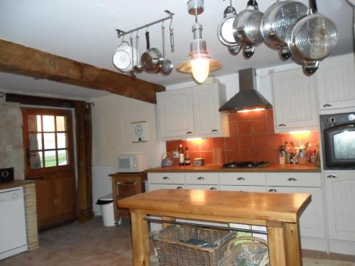 une cuisine avec des armoires blanches et une table en bois dans l'établissement '1786' au bourg, à Mansonville