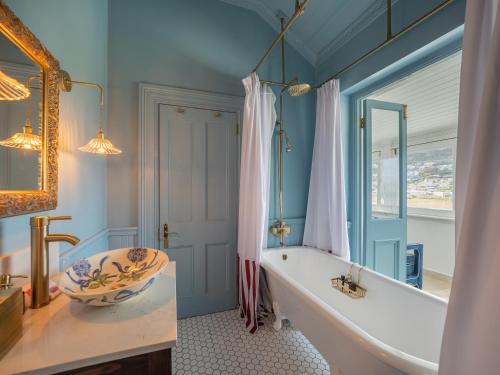 a bathroom with a tub and a sink and a mirror at Tintswalo Summer House in Glencairn