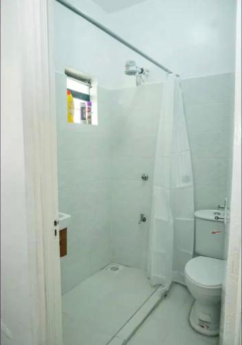 a white bathroom with a shower and a toilet at Omtush Suites 002 in Marimbeti