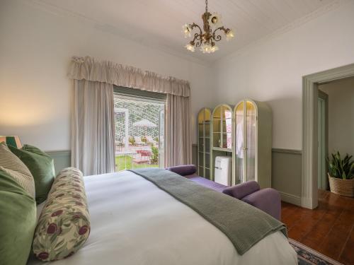 a bedroom with a bed and a window with surfboards at Tintswalo Summer House in Glencairn
