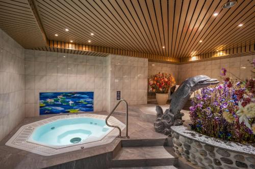 Ein Badezimmer mit einer Badewanne und einem Dinosaurier neben einem Fernseher in der Unterkunft Hotel Simi in Zermatt