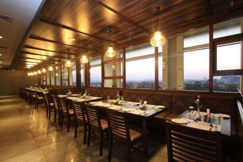 a dining room with tables and chairs and windows at Icon Business Hotel by Bhagini in Bangalore