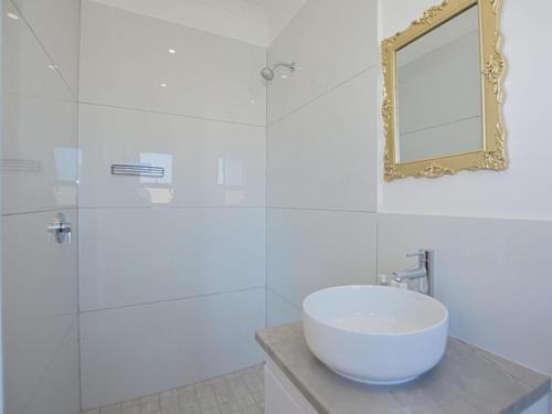a white bathroom with a sink and a mirror at Blouberg Studio Apartments in Cape Town